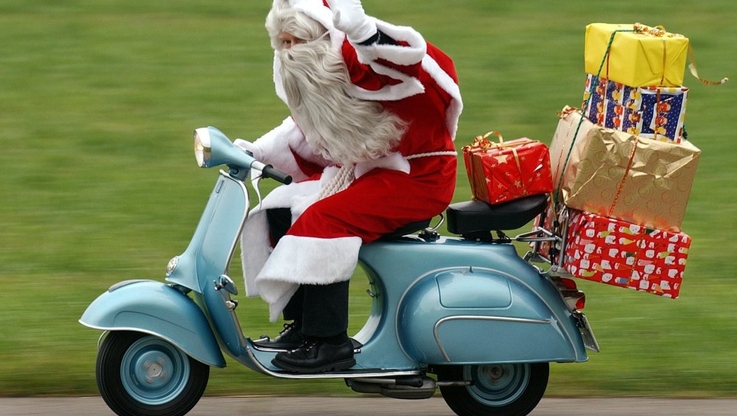 A Santa Claus races on a vintage vespa bike to deliver presents